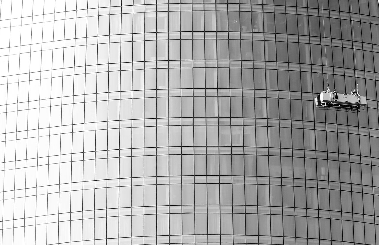 High-rise glass facade with suspended platform for window cleaning.